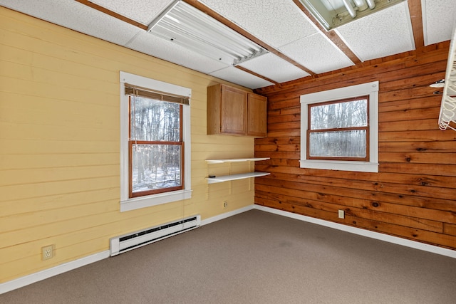 spare room featuring carpet flooring, wood walls, and baseboard heating