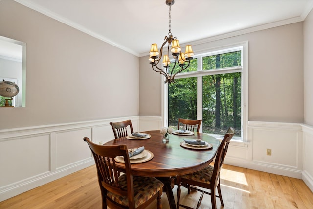 dining room with a notable chandelier, light wood-type flooring, and ornamental molding