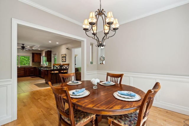 dining space featuring ceiling fan with notable chandelier, light wood-type flooring, and crown molding