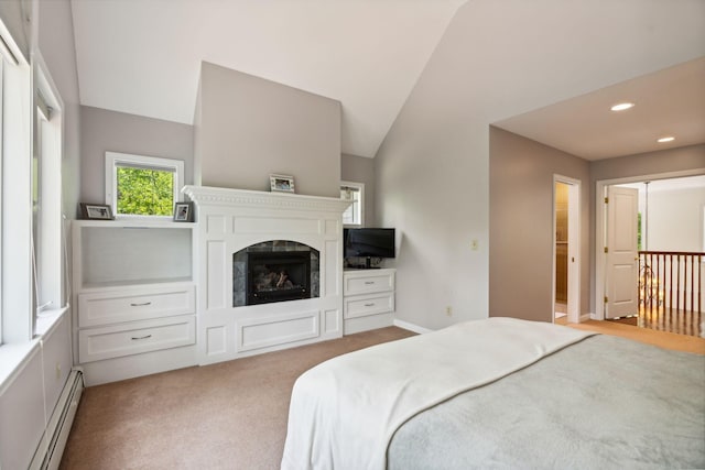 carpeted bedroom featuring lofted ceiling, a baseboard heating unit, and connected bathroom