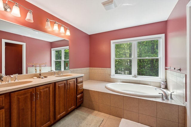 bathroom featuring a healthy amount of sunlight, tile patterned flooring, vanity, and tiled tub