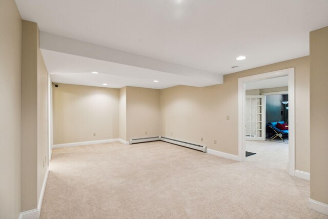 basement with baseboard heating and light colored carpet