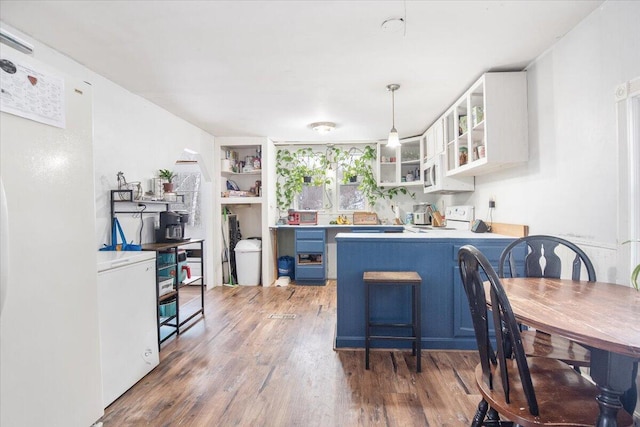 kitchen featuring hanging light fixtures, white range with electric stovetop, dark hardwood / wood-style flooring, a kitchen bar, and white cabinetry