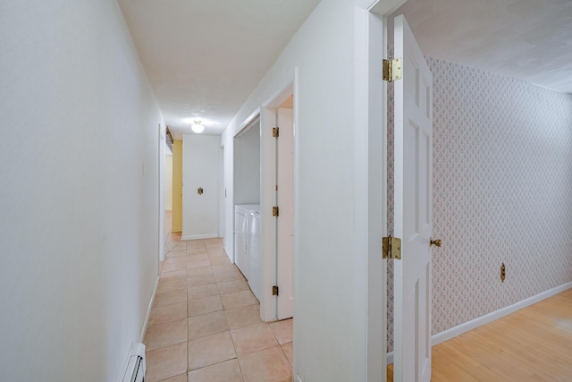 hall featuring a baseboard heating unit, washing machine and dryer, and light tile patterned floors