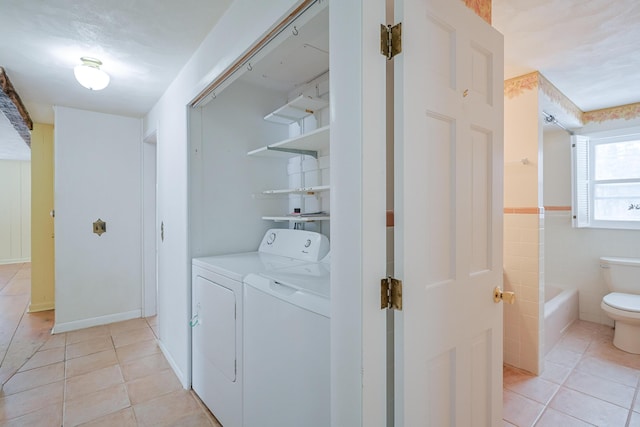 laundry room featuring washer and dryer, tile walls, and light tile patterned floors