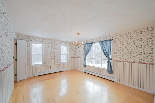 bonus room featuring wood-type flooring, a baseboard radiator, and a notable chandelier