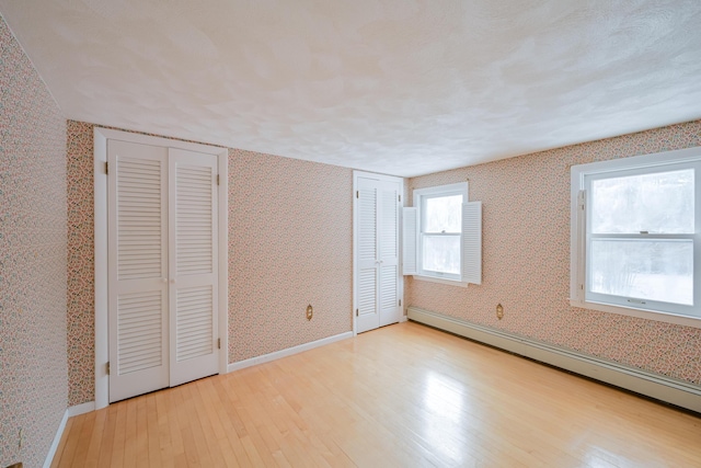 unfurnished bedroom featuring a baseboard radiator and light wood-type flooring