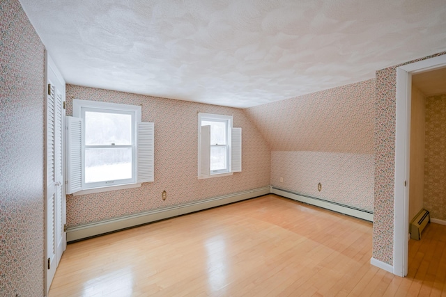 bonus room featuring light hardwood / wood-style floors, lofted ceiling, and a baseboard heating unit