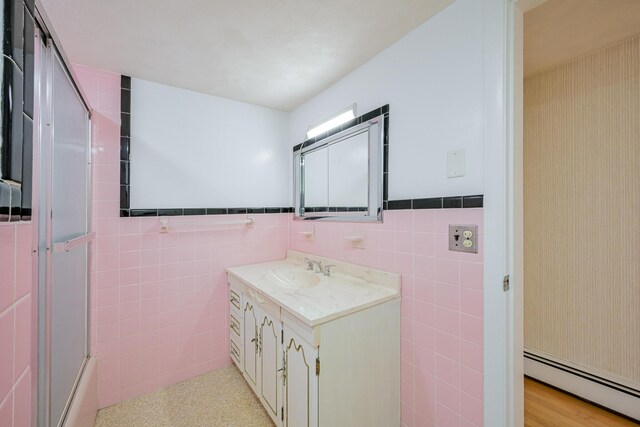 bathroom with tile walls, a baseboard radiator, and vanity