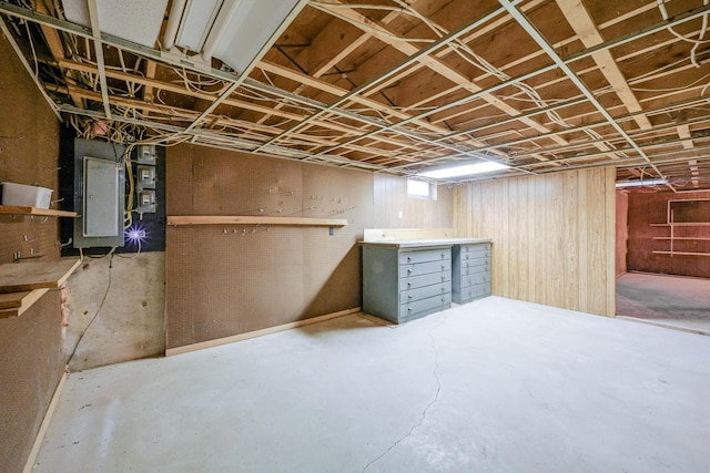 basement with wood walls, electric panel, and a workshop area