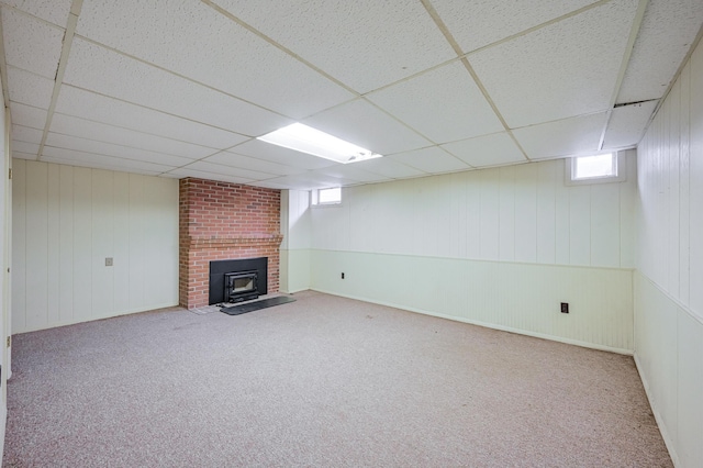 basement featuring carpet, a wood stove, and a drop ceiling