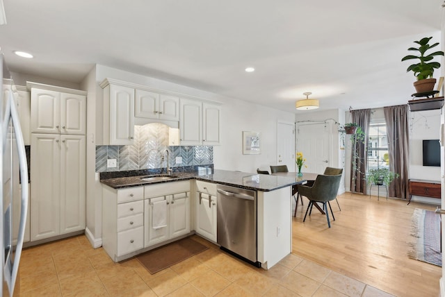 kitchen with stainless steel appliances, sink, white cabinetry, dark stone countertops, and kitchen peninsula