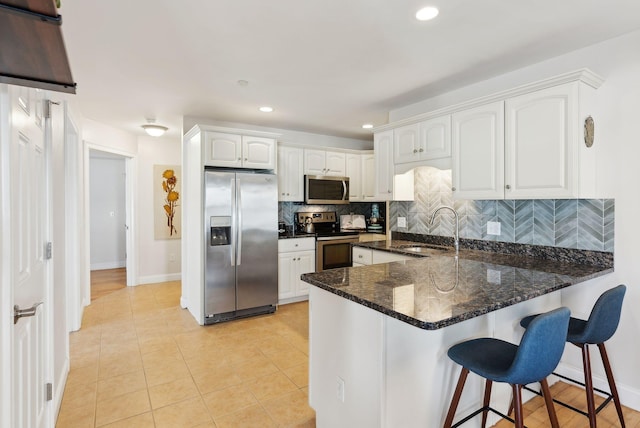 kitchen with kitchen peninsula, stainless steel appliances, light tile patterned floors, white cabinetry, and sink