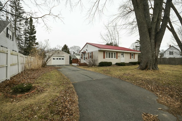 view of front of property featuring a front lawn, a garage, and an outbuilding