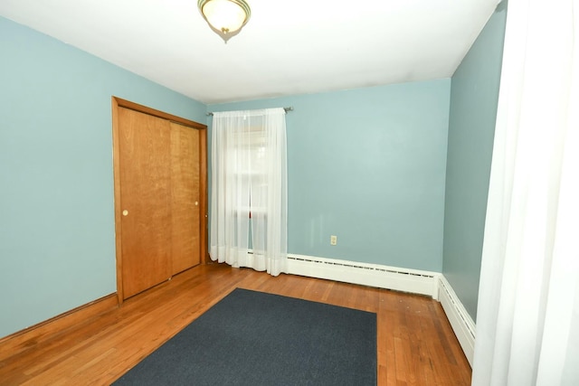 spare room featuring baseboard heating and hardwood / wood-style flooring