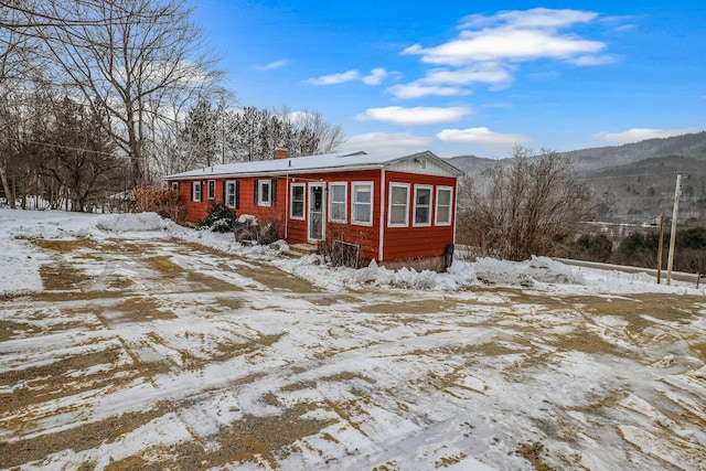 snow covered back of property featuring a mountain view