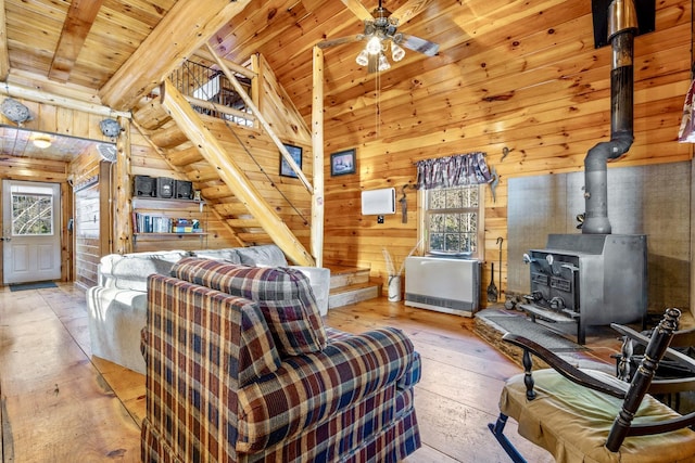 living room featuring light wood-type flooring, wooden ceiling, plenty of natural light, and a wood stove