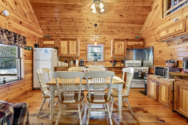 kitchen featuring white appliances, hanging light fixtures, wood walls, light hardwood / wood-style floors, and wood ceiling