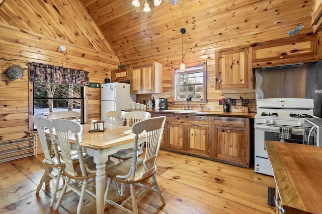 kitchen with sink, decorative light fixtures, white appliances, light hardwood / wood-style floors, and butcher block countertops