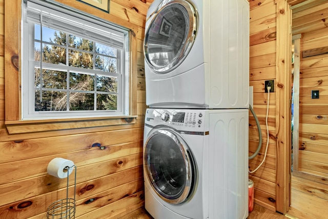 washroom featuring stacked washer / drying machine and wood walls