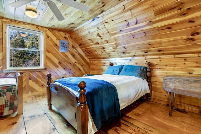 bedroom with wooden ceiling, wood walls, ceiling fan, hardwood / wood-style flooring, and lofted ceiling