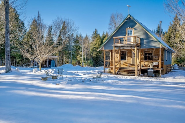 snow covered property featuring a porch and a balcony