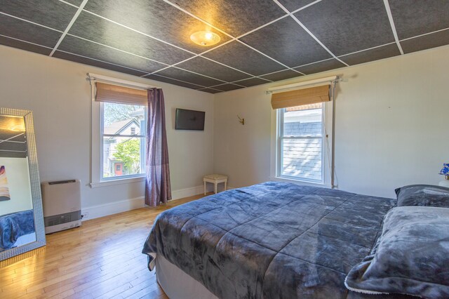 bedroom featuring heating unit, baseboards, and hardwood / wood-style floors