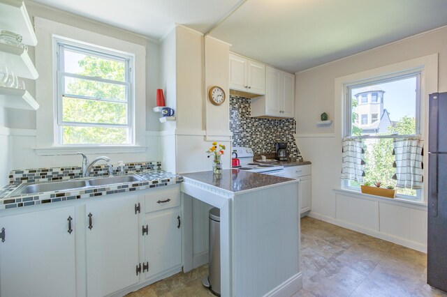 kitchen featuring backsplash, white cabinetry, electric stove, and a sink