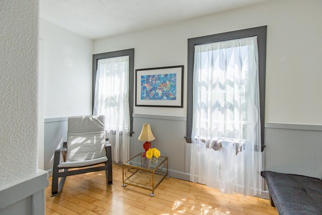 living area with wood finished floors and wainscoting