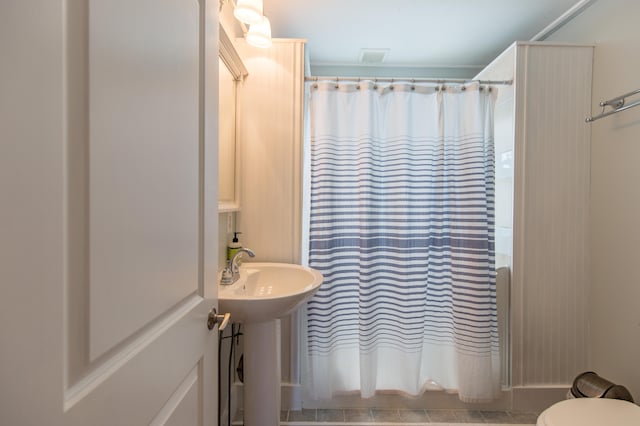 full bath featuring a sink, shower / bathtub combination with curtain, and toilet