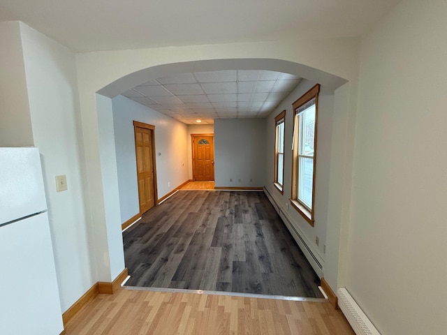 hallway with a paneled ceiling, hardwood / wood-style floors, and a baseboard heating unit