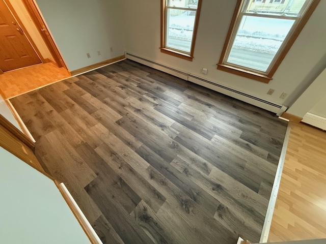 unfurnished bedroom featuring a baseboard heating unit and hardwood / wood-style floors