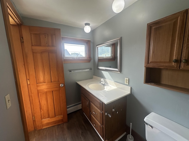 bathroom with wood-type flooring, a baseboard heating unit, vanity, and toilet