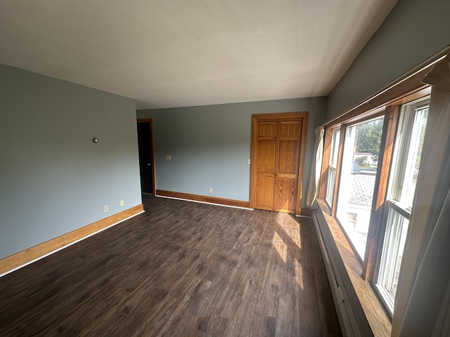 spare room with dark hardwood / wood-style floors and a baseboard heating unit