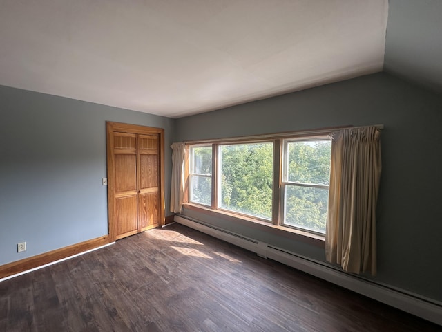 unfurnished bedroom featuring a baseboard heating unit, vaulted ceiling, and dark hardwood / wood-style floors