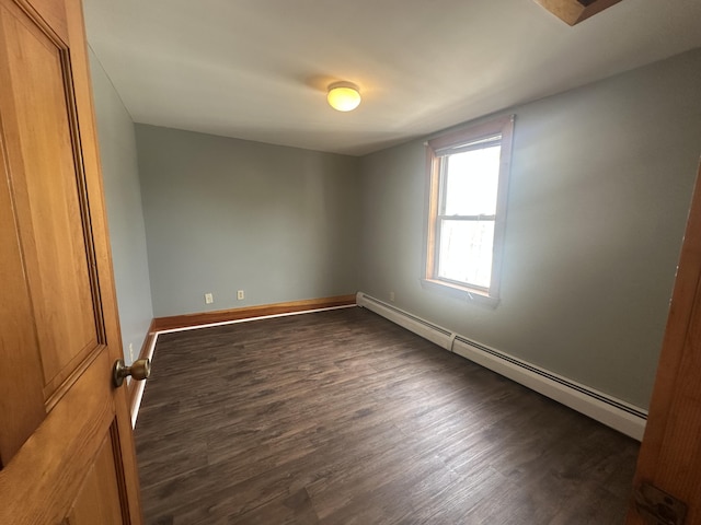 empty room with baseboard heating and dark wood-type flooring