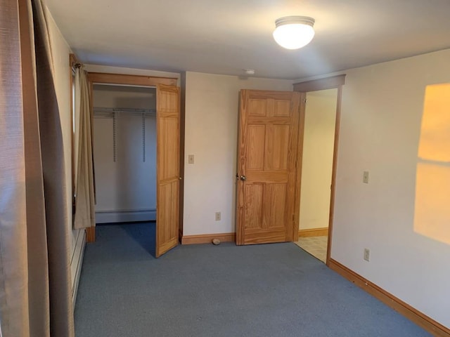 unfurnished bedroom with baseboard heating, a closet, and dark carpet