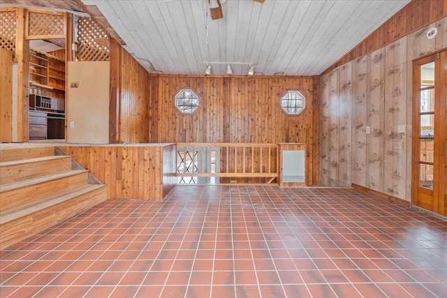 unfurnished room with wood walls, ceiling fan, and tile patterned floors