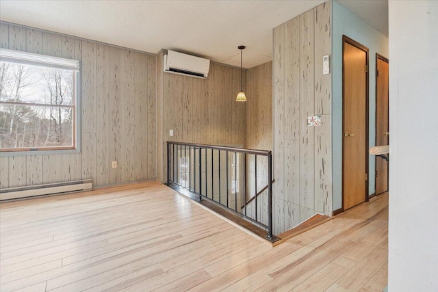 unfurnished room with wooden walls, a baseboard radiator, a wall unit AC, and wood-type flooring