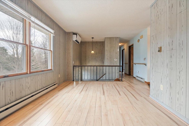 unfurnished room with baseboard heating, a wall mounted AC, wood walls, and hardwood / wood-style floors