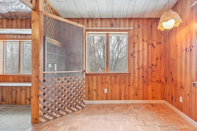 unfurnished room with a wealth of natural light, wooden ceiling, wood walls, and light parquet flooring