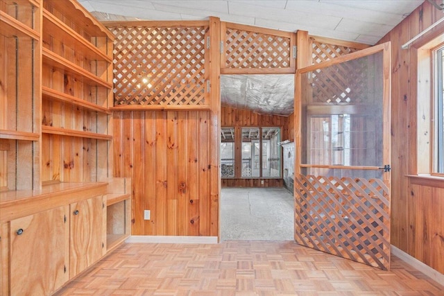 interior space with wood walls, lofted ceiling, and light parquet floors