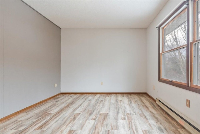 empty room with a baseboard radiator and light hardwood / wood-style flooring