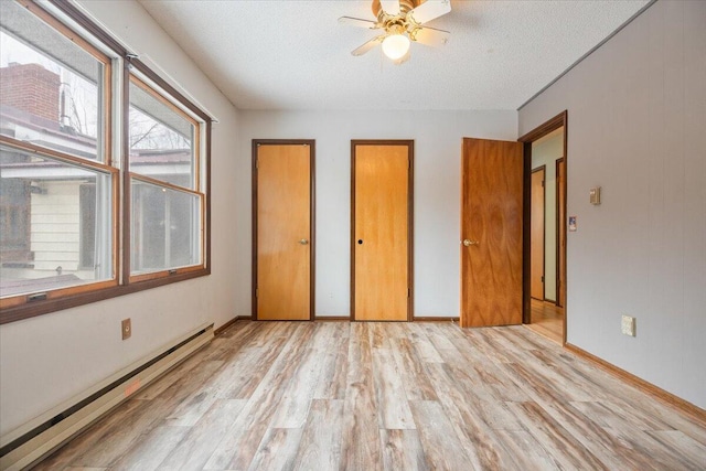 unfurnished bedroom featuring a baseboard heating unit, ceiling fan, a textured ceiling, and light wood-type flooring