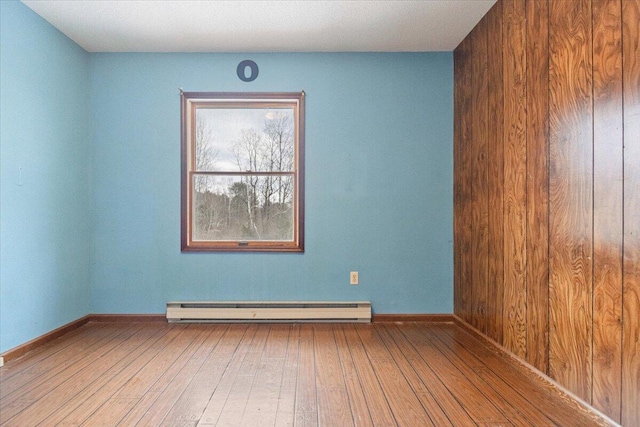 empty room featuring a baseboard heating unit and hardwood / wood-style flooring