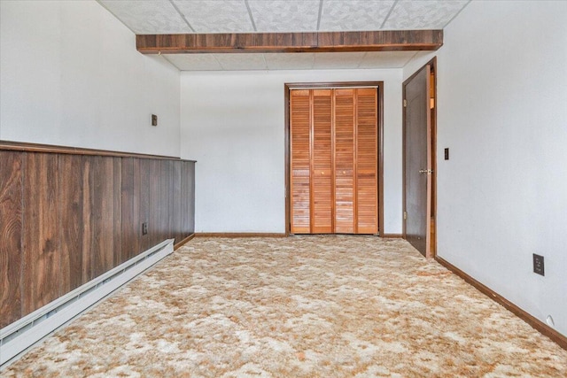 carpeted spare room with a baseboard heating unit