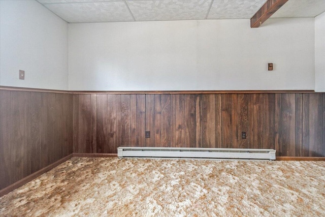 unfurnished room featuring wooden walls, carpet floors, and baseboard heating