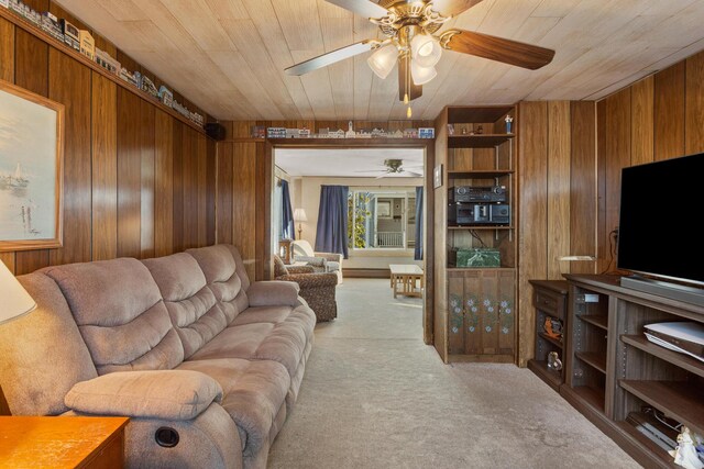 living room featuring wood ceiling, light colored carpet, ceiling fan, and wood walls