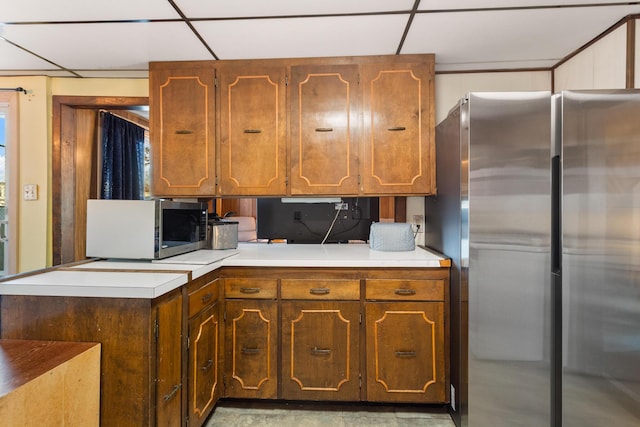 kitchen with appliances with stainless steel finishes, a paneled ceiling, and kitchen peninsula