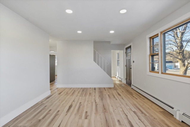 unfurnished room with a baseboard radiator and light wood-type flooring